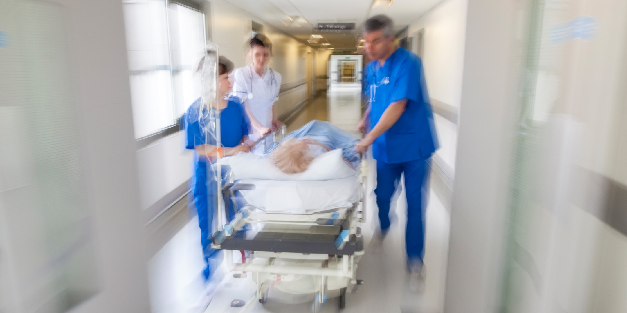 A person being rushed in an medical emergency down the hall in a hospital.